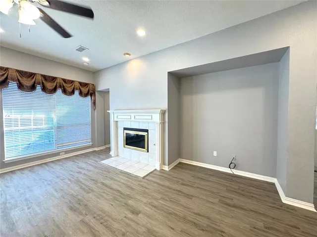 a view of an empty room with wooden floor and a fireplace