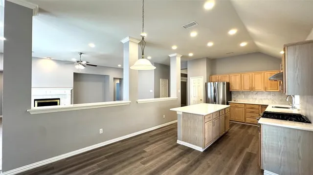 a large kitchen with kitchen island a stove a sink dishwasher and white cabinets with wooden floor