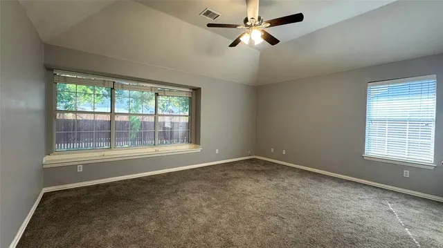 a view of empty room with ceiling fan and window