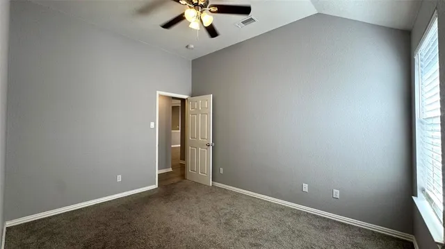 an empty room with a window and a chandelier fan