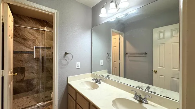 a bathroom with a granite countertop sink a mirror and shower