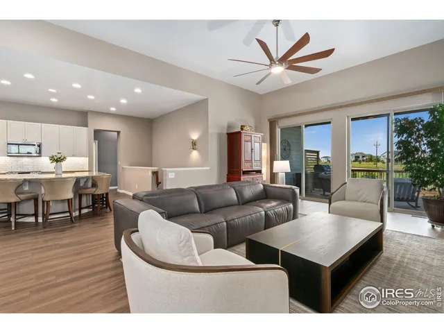 a living room with furniture kitchen view and a wooden floor