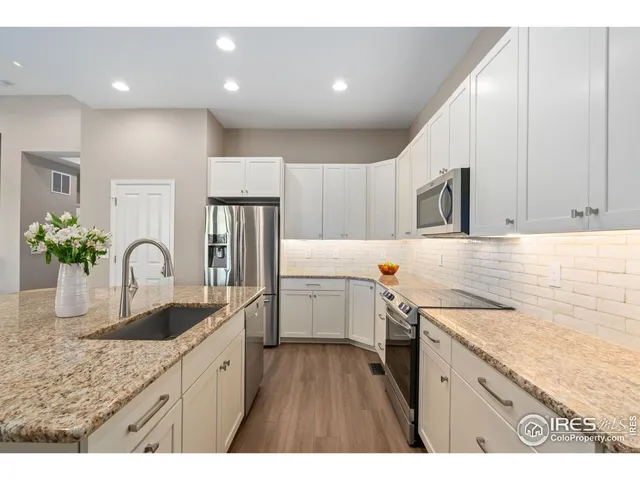 a kitchen with a sink dishwasher a stove top oven a refrigerator with wooden cabinets and floor