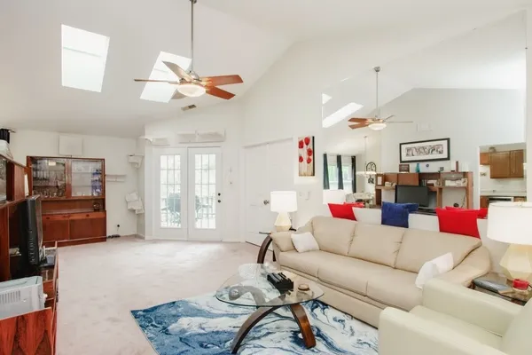 a living room with furniture kitchen view and a wooden floor