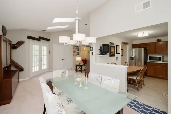 a dining room with wooden floor a chandelier a wooden table and chairs