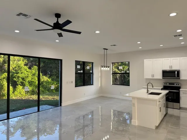 a living room with stainless steel appliances kitchen island furniture and a large window