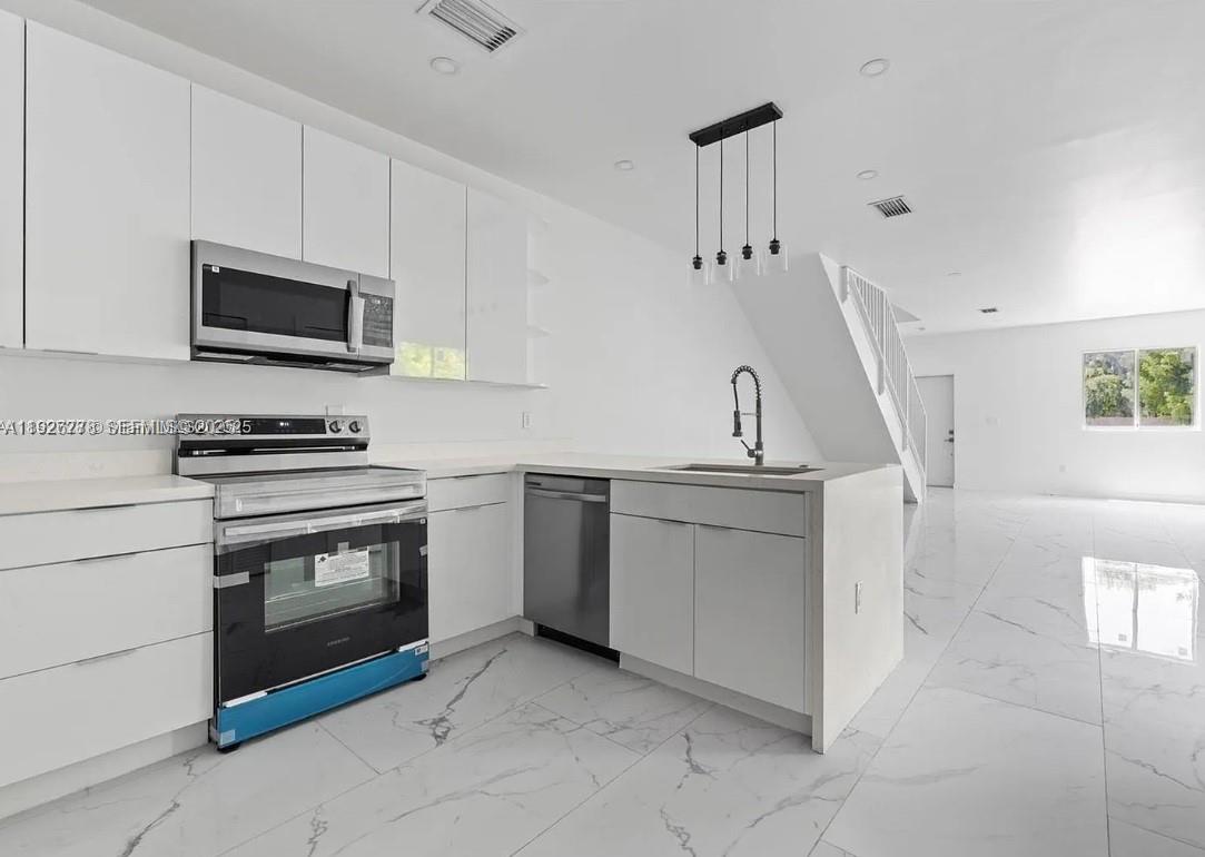 2145 Northwest 4th Street, Unit 2145 Pompano Beach, FL 33069 - Photo 5 of 13 a kitchen with granite countertop a sink and a stove top oven