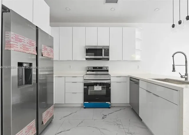 a kitchen with stainless steel appliances granite countertop a refrigerator and a stove top oven