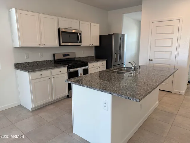 a kitchen with kitchen island granite countertop stainless steel appliances a stove microwave and sink