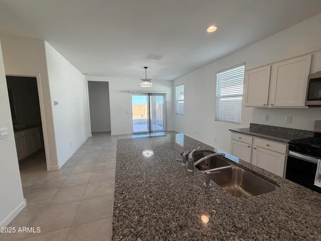 a kitchen with granite countertop a sink a stove and refrigerator