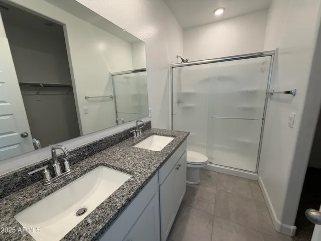 a bathroom with a granite countertop sink a toilet and shower