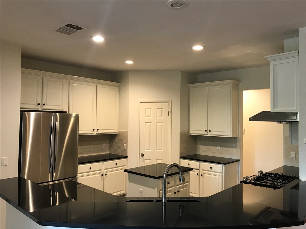 6428 Ruxton Lane Austin, TX 78749 - Photo 4 of 23 a kitchen with granite countertop cabinets a refrigerator and a stove top oven with wooden floor