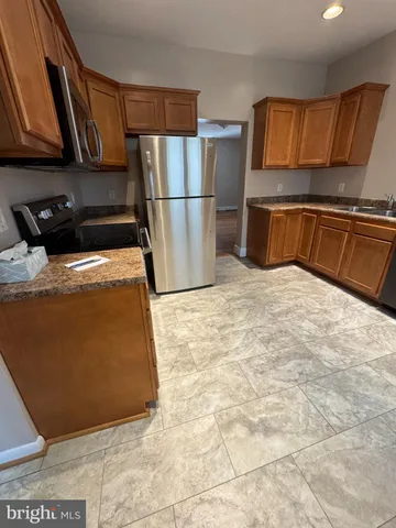 a kitchen with stainless steel appliances granite countertop a refrigerator a stove a sink dishwasher and microwave