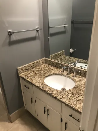 a bathroom with a granite countertop sink and a mirror