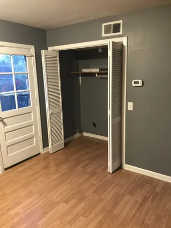 an empty room with wooden floor closet and windows