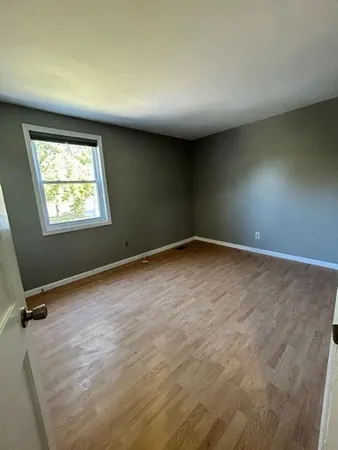 an empty room with wooden floor cabinet and windows