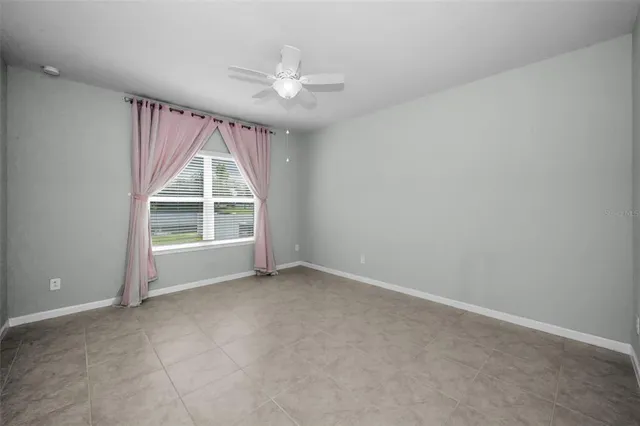 an empty room with windows and chandelier fan