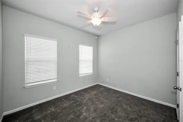 an empty room with windows and ceiling fan