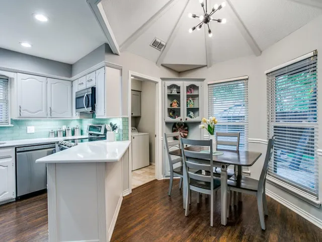 a kitchen with stainless steel appliances granite countertop a stove a sink dishwasher a dining table and chairs with wooden floor