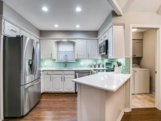 a kitchen with white cabinets and stainless steel appliances
