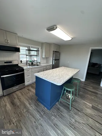 a kitchen with granite countertop a stove a sink and a wooden floors