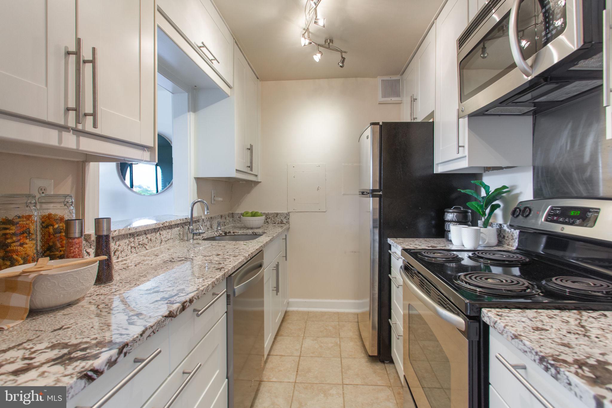 2501 Calvert Street Northwest, Unit 802 Washington, DC 20008 - Photo 5 of 20 a kitchen with stainless steel appliances granite countertop a sink stove and refrigerator