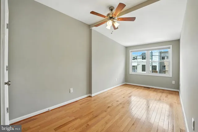 an empty room with wooden floor chandelier fan and windows