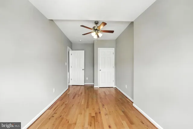 a view of a room with wooden floor and a ceiling fan