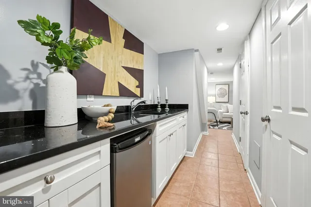 a hallway with white cabinets and chandelier