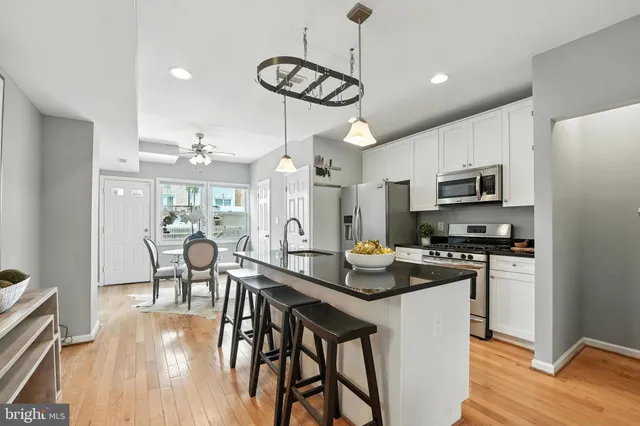 a kitchen with stainless steel appliances granite countertop a stove a refrigerator a kitchen island a dining table and chairs with wooden floor