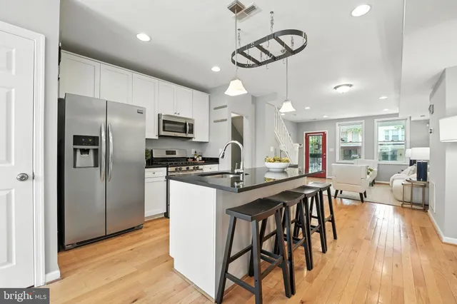 a kitchen with stainless steel appliances granite countertop a dining table chairs refrigerator and microwave