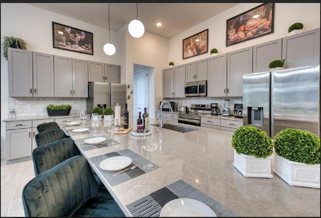 6301 Sand Skipper Road Orlando, FL 32821 - Photo 16 of 80 a kitchen with stainless steel appliances kitchen island granite countertop a refrigerator a stove a microwave oven a sink with island and chairs