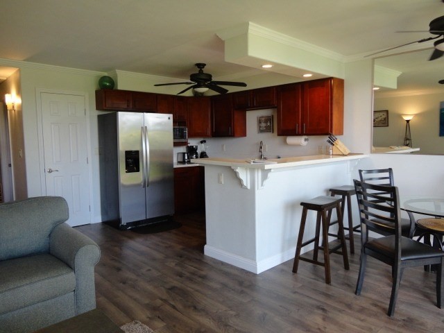 5050 Lawai Road, Unit 101 Koloa, HI 96756 - Photo 11 of 24 a kitchen with stainless steel appliances kitchen island granite countertop a refrigerator a stove a microwave oven a dining table and chairs with wooden floor