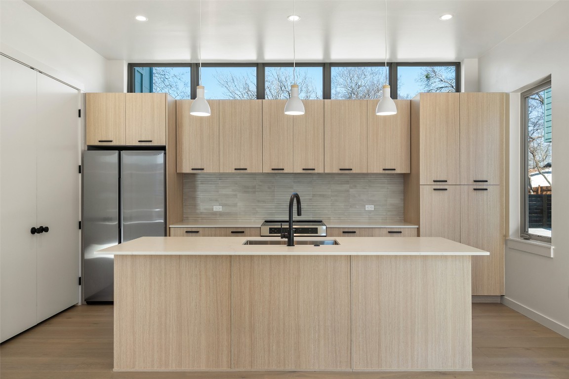 a view of kitchen with stainless steel appliances granite countertop a refrigerator a sink and white cabinets