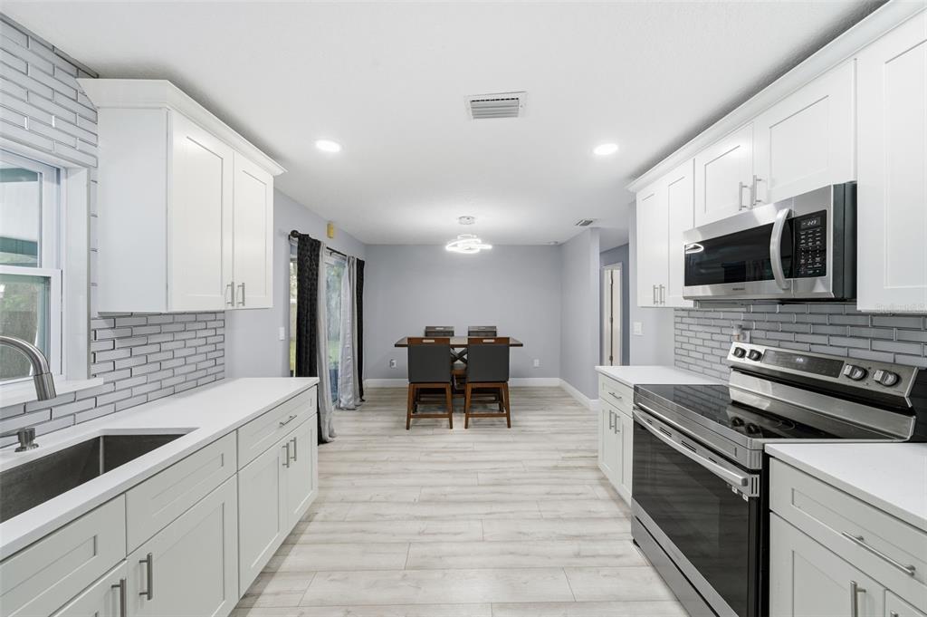 1113 Oakhill Street Seffner, FL 33584 - Photo 6 of 44 a large white kitchen with stainless steel appliances granite countertop a stove and a sink