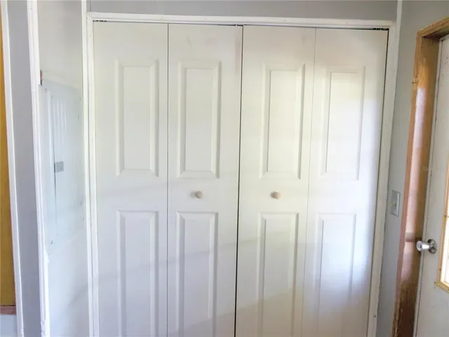 an empty room with a chandelier fan and windows