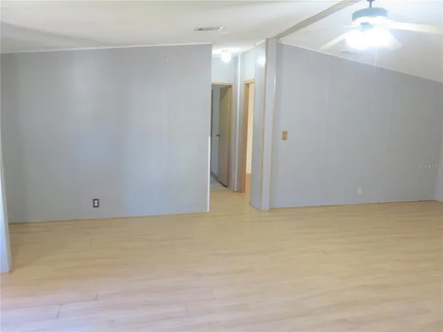an empty room with windows and ceiling fan