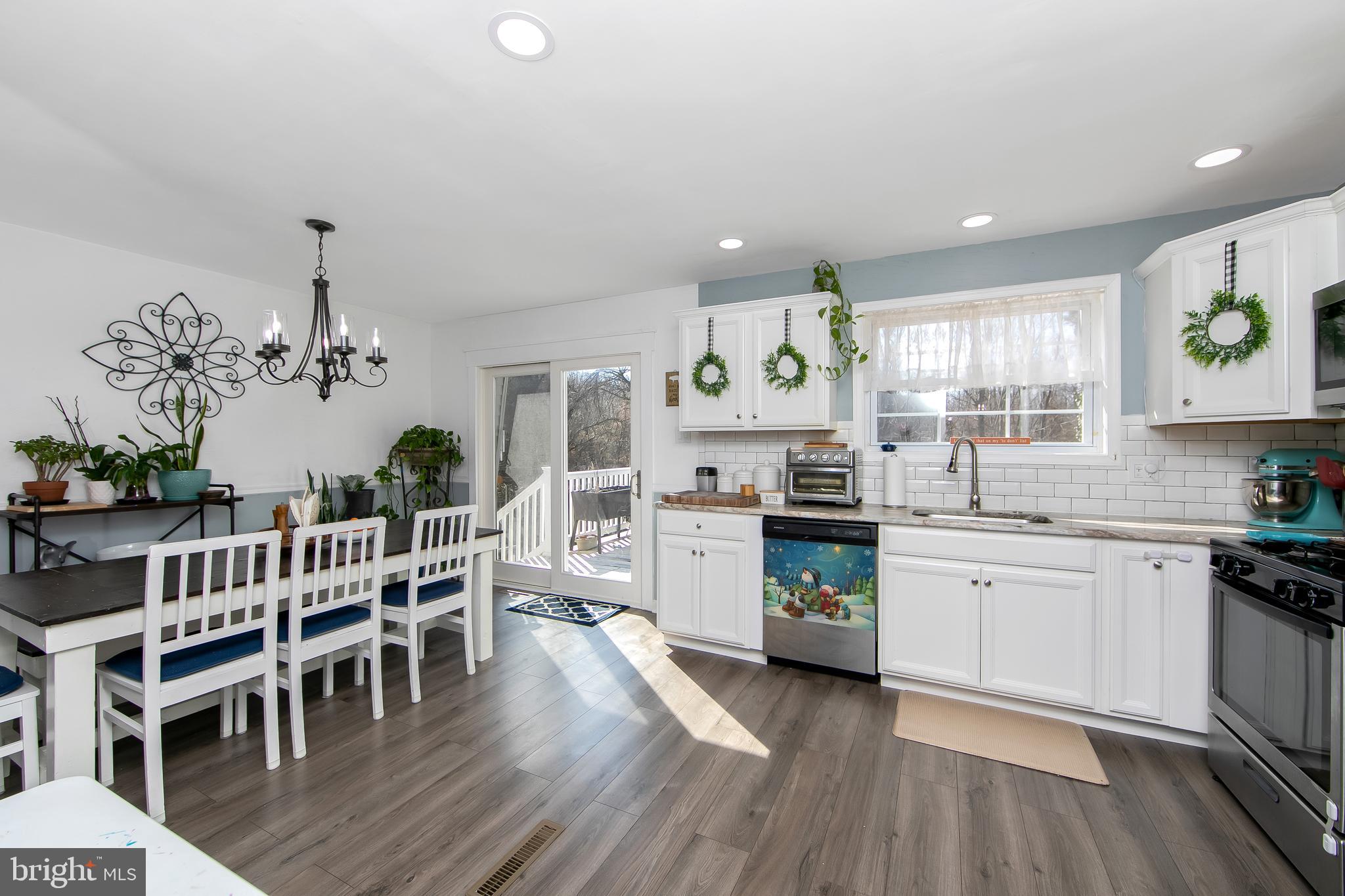 121 Capella Road Sewell, NJ 08080 - Photo 11 of 29 a kitchen with stainless steel appliances granite countertop wooden floors a stove a dining table and chairs