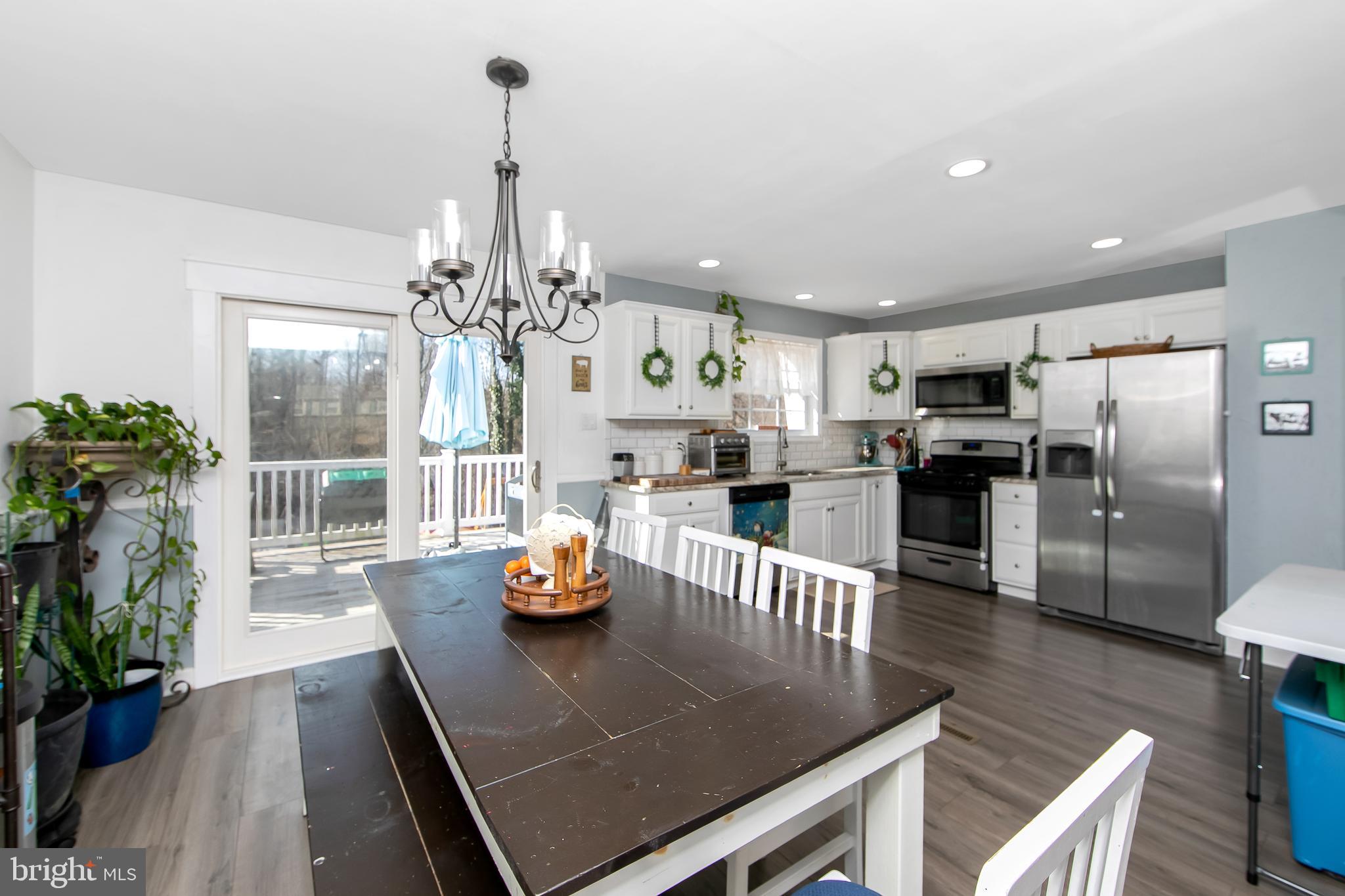 121 Capella Road Sewell, NJ 08080 - Photo 6 of 29 a kitchen with stainless steel appliances granite countertop a refrigerator a oven a stove and a dining table with wooden floor