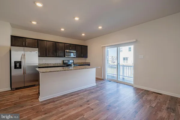 a kitchen with stainless steel appliances granite countertop a refrigerator a sink dishwasher a stove and a microwave oven with wooden floor