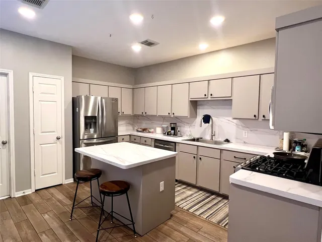 a kitchen with a sink a stove a refrigerator and white cabinets