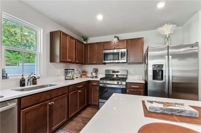 a kitchen with stainless steel appliances granite countertop a refrigerator a sink dishwasher a stove top oven a refrigerator with wooden cabinets and floor
