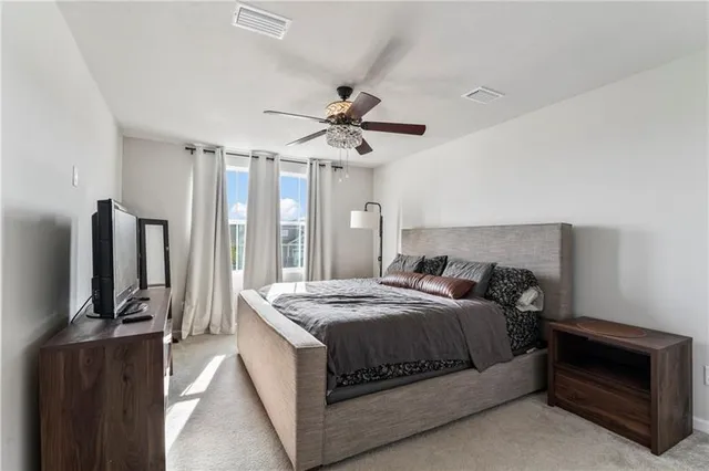 a bedroom with a bed a flat screen tv and a large window
