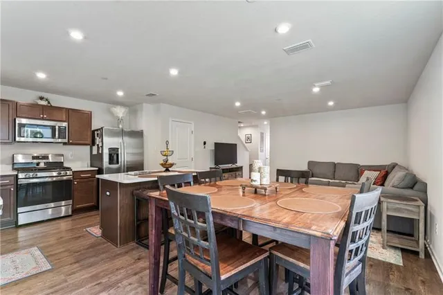 a kitchen with stainless steel appliances kitchen island granite countertop a table chairs and a stove top oven with wooden floor