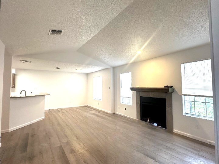 a view of empty room with wooden floor and fireplace