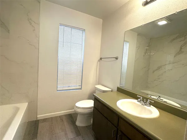 a bathroom with a granite countertop sink toilet a mirror and a bathtub