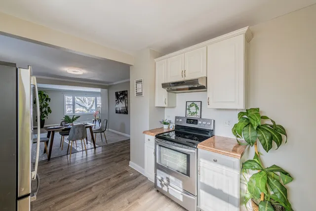 a kitchen with granite countertop a stove a sink a dining table and chairs with wooden floor