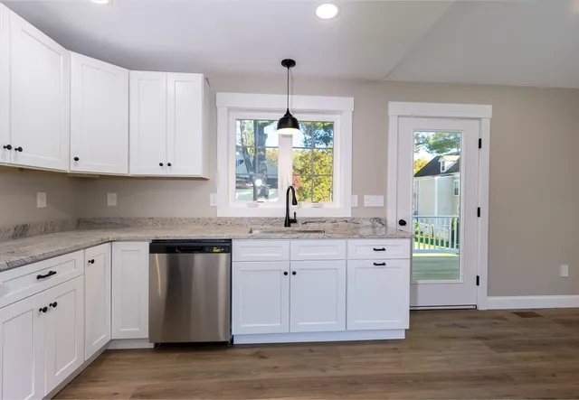 a kitchen with granite countertop a white cabinets and window