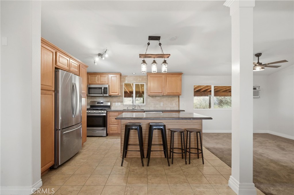 40100 Owl Valley Road Temecula, CA 92592 - Photo 24 of 44 a kitchen with kitchen island granite countertop wooden cabinets and stainless steel appliances