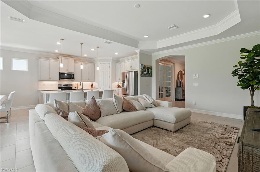 28165 Captiva Shell Loop Bonita Springs, FL 34135 - Photo 10 of 38 Kitchen featuring appliances with stainless steel finishes, backsplash, crown molding, a breakfast bar area, and a center island with sink